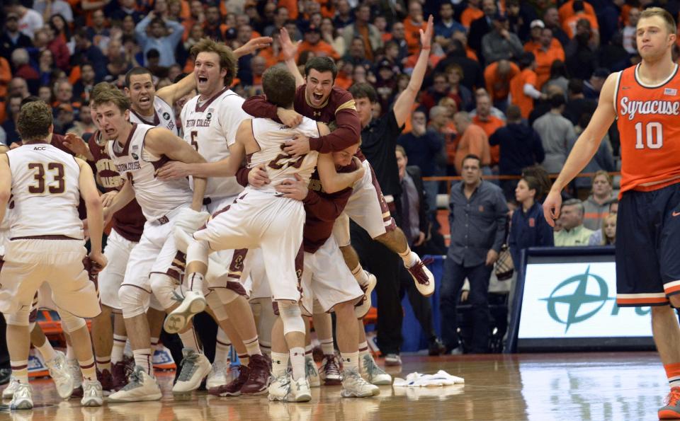 Boston College players celebrate after defeating Syracuse 62-59 in overtime as Syracuse's Trevor Cooney, right, walks off the court following an NCAA college basketball game in Syracuse, N.Y., Wednesday, Feb. 19, 2014. (AP Photo/Kevin Rivoli)