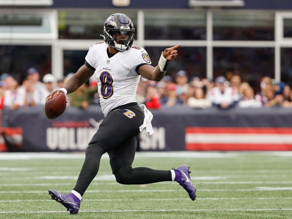 Lamar Jackson signals while running with the ball against the New England Patriots.