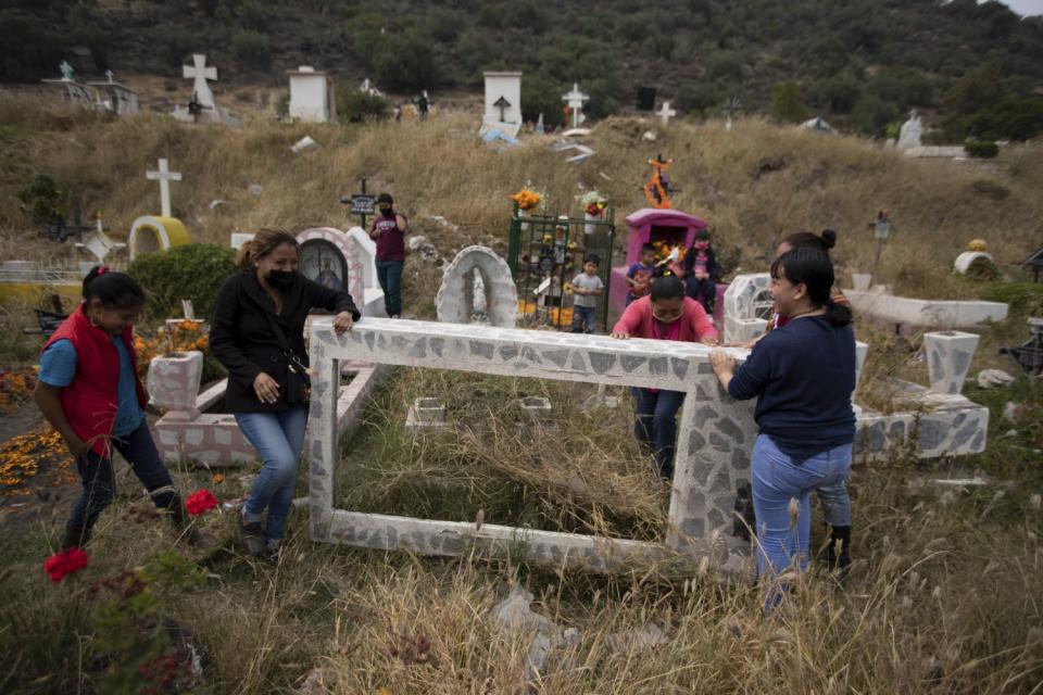 People lift up a gravestone to clean it