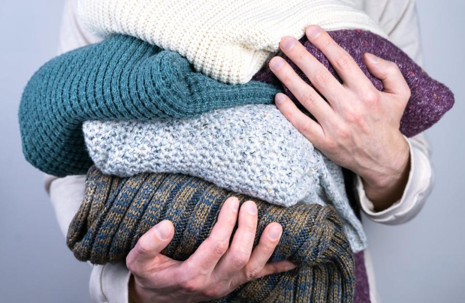 Men's hands hold warm knitted sweaters. Warm winter clothes. 