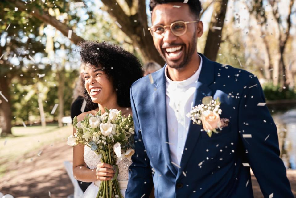 <p>Foto de una joven pareja de recién casados feliz recibiendo una lluvia de confeti al aire libre el día de su boda.</p> (Getty Images)