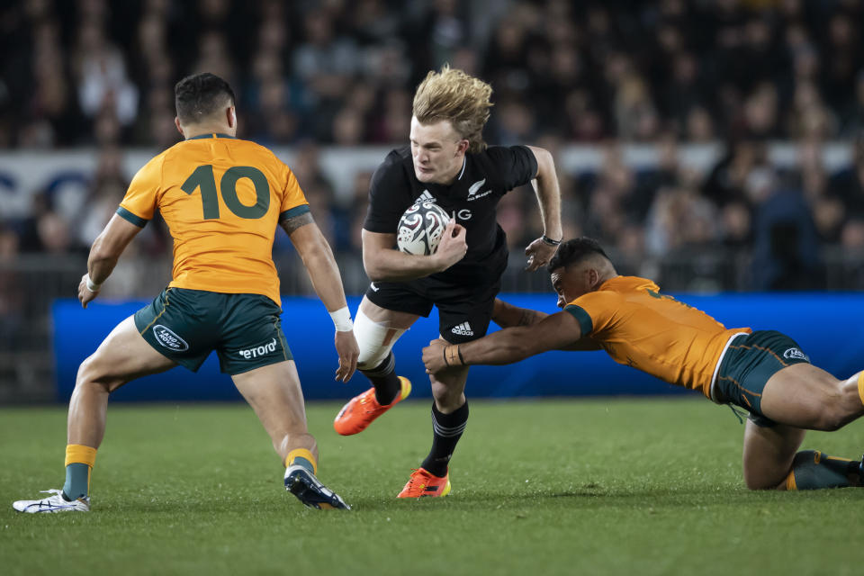 New Zealand's Damian McKenzie, center, is tackled by Australia's Noah Lolesio, left, and Hunter Paisami during their Bledisloe Cup rugby union test match at Eden Park in Auckland, New Zealand, Saturday, Aug. 7, 2021. (Brett Phibbs/Photosport via AP)