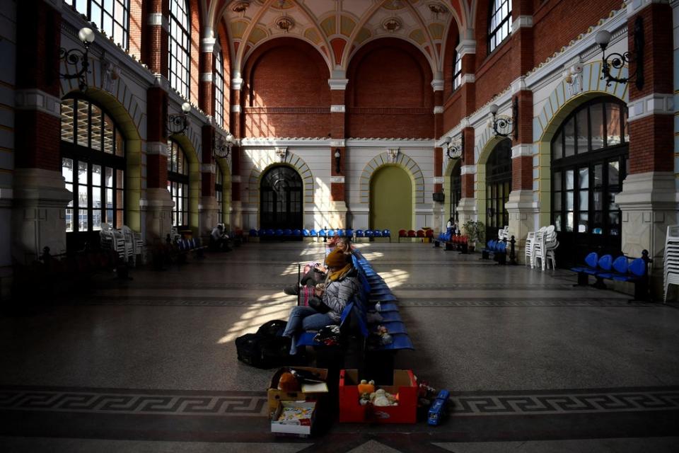 People sit near food which has been left for Ukrainian refugees in the waiting hall at Suceava train station (Reuters)