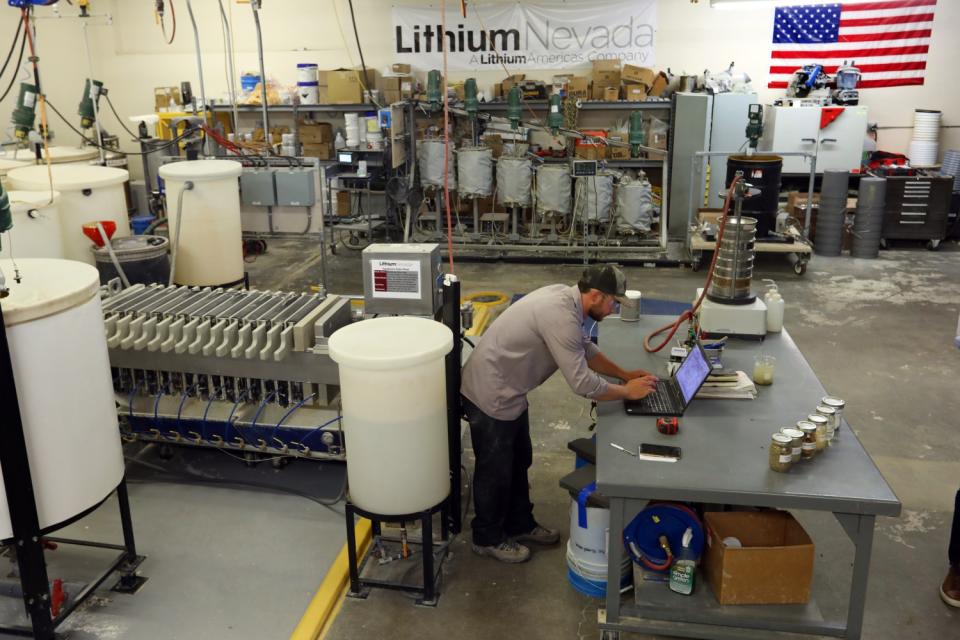 A technician at Lithium Americas bends over a laptop amid equipment in a large lab.