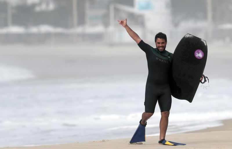 El bodyboarder Bruno Salgado, de 23 años, saluda en la playa de Copacabana, en medio de la epidemia de COVID-19, la enfermedad que causa el coronavirus, en Rio de Janeiro