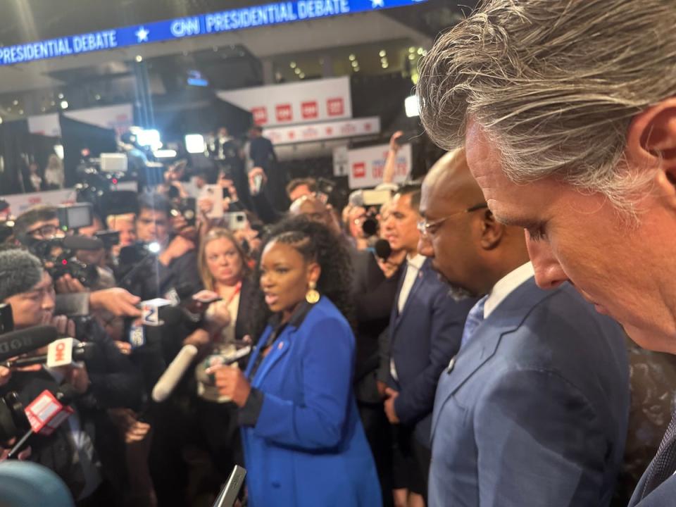 Rep Jasmine Crockett speaks as Senator Raphael Warnock and Gavin Newsom look on. Newsom said that he ‘would never turn [his] back’ on President Biden (The Independent/Andrew Feinberg)