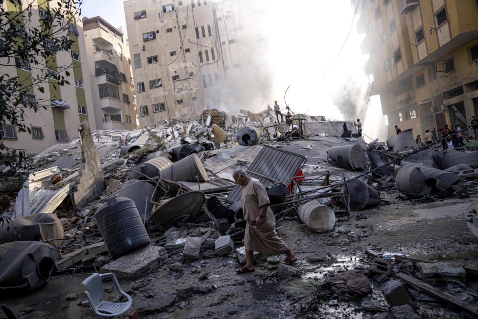 Palestinians inspect the rubble of a building after it was struck by an Israeli airstrike, in Gaza City, Saturday, Oct. 7, 2023. The militant Hamas rulers of the Gaza Strip carried out an unprecedented, multi-front attack on Israel at daybreak Saturday, firing thousands of rockets as dozens of Hamas fighters infiltrated the heavily fortified border in several locations by air, land, and sea and catching the country off-guard on a major holiday. (AP Photo/Fatima Shbair)