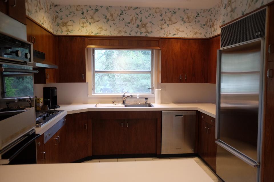 BEFORE: Pre-renovation, the kitchen featured floral wallpaper, Formica countertops, and a suite of aging appliances.