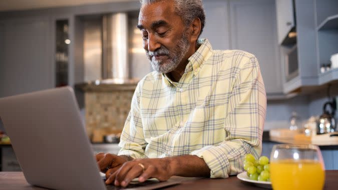 Smiling man using laptop at home.