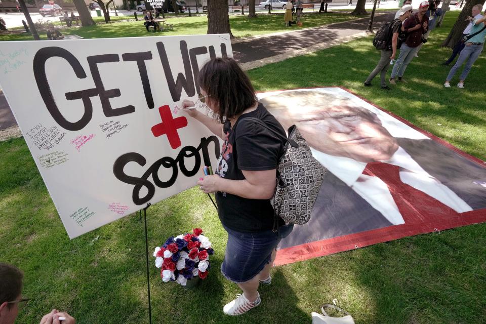 A woman sign a canvas with get well wishes for former President Trump during a Prayer Vigil for America Sunday, July 14, 2024 at Zeidler Union Square in Milwaukee, Wisconsin. The park is located five blocks from Fiserv Forum, site of the Republican National Convention that starts Monday.
