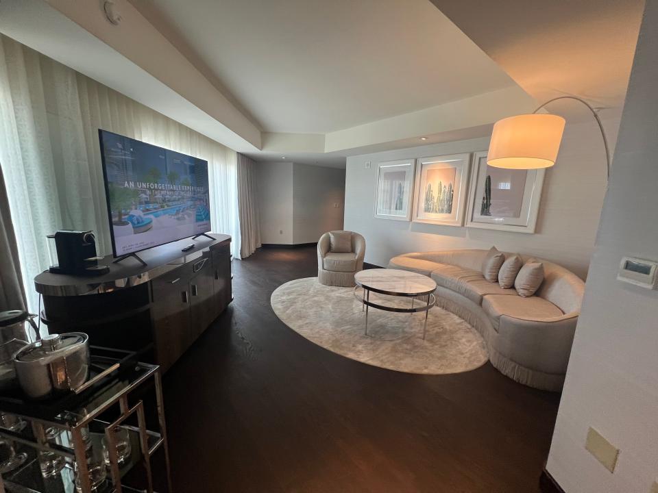 A living room area in a hotel suite with a couch, TV, and bar area.