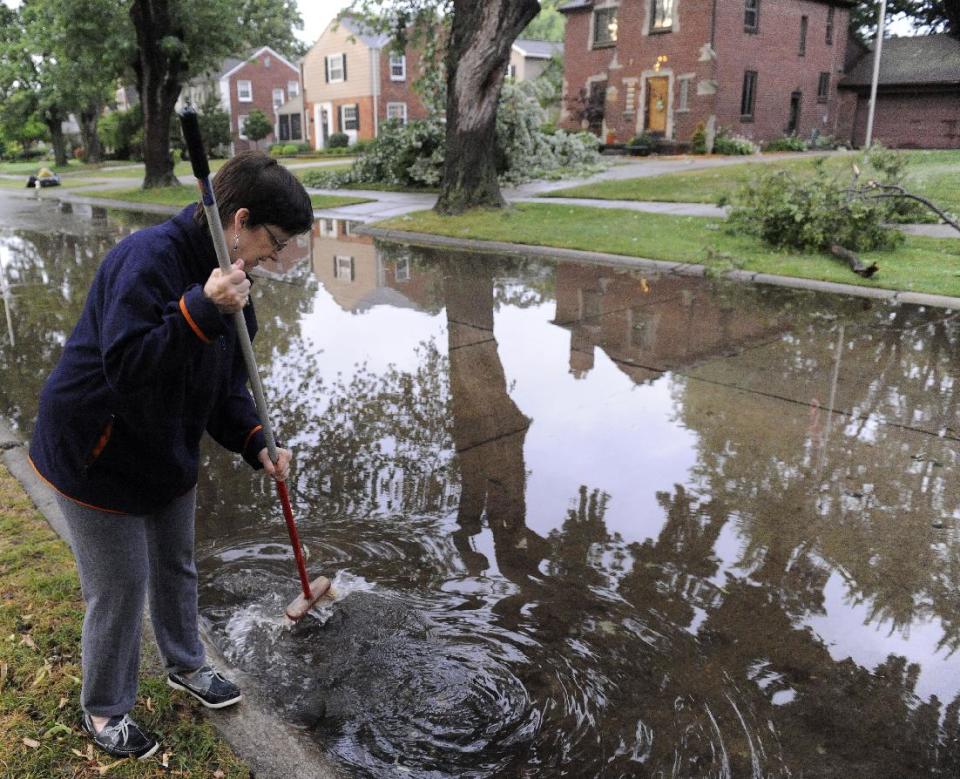 Kathy Konwiak clears a storm drain in front of her home in Grosse Pointe Woods, Michigan on Thursday, July 5, 2012 after thunderstorms pummeled southeastern Michigan Thursday morning. DTE Energy Co. says about 200,000 of its customers were without power Thursday morning after a new round of damaging thunderstorms made its way across the state, knocking down trees and power lines. (AP Photo/The Detroit News, David Coates) DETROIT FREE PRESS OUT; HUFFINGTON POST OUT. NO MAGS. NO SALES. MANDATORY CREDIT