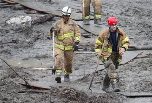 Snohomish County firefighters walk through the mud on a plywood path at the west side of the mudslide on Highway 530 near mile marker 37 on Sunday, March 30, 2014, in Arlington, Wash. Periods of rain and wind have hampered efforts the past two days, with some rain showers continuing today. (AP Photo/Rick Wilking, Pool)