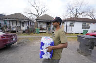 Ernest Collins carries cases of water back to his home, which was without running water for days after a recent winter storm, Friday, Feb. 26, 2021, in Houston. Local officials, including Houston Mayor Sylvester Turner, say they have focused their efforts during the different disasters on helping the underserved and under-resourced but that their work is far from complete. (AP Photo/David J. Phillip)