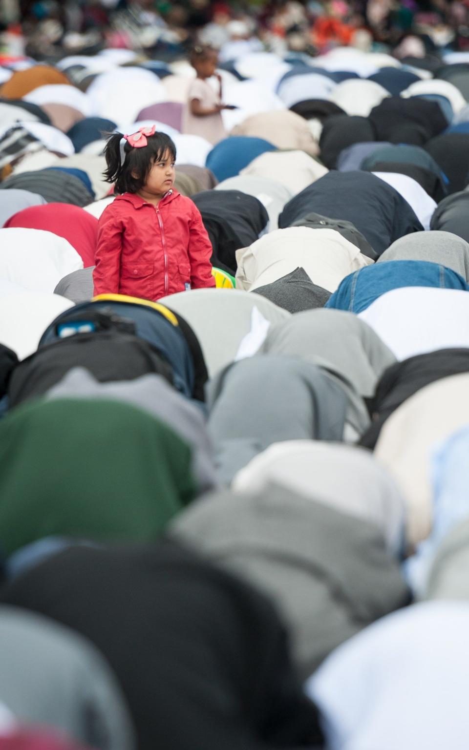 A young girl remains standing amongst the sea of muslim faithful as they take part in prayers - Credit:  Lee Thomas