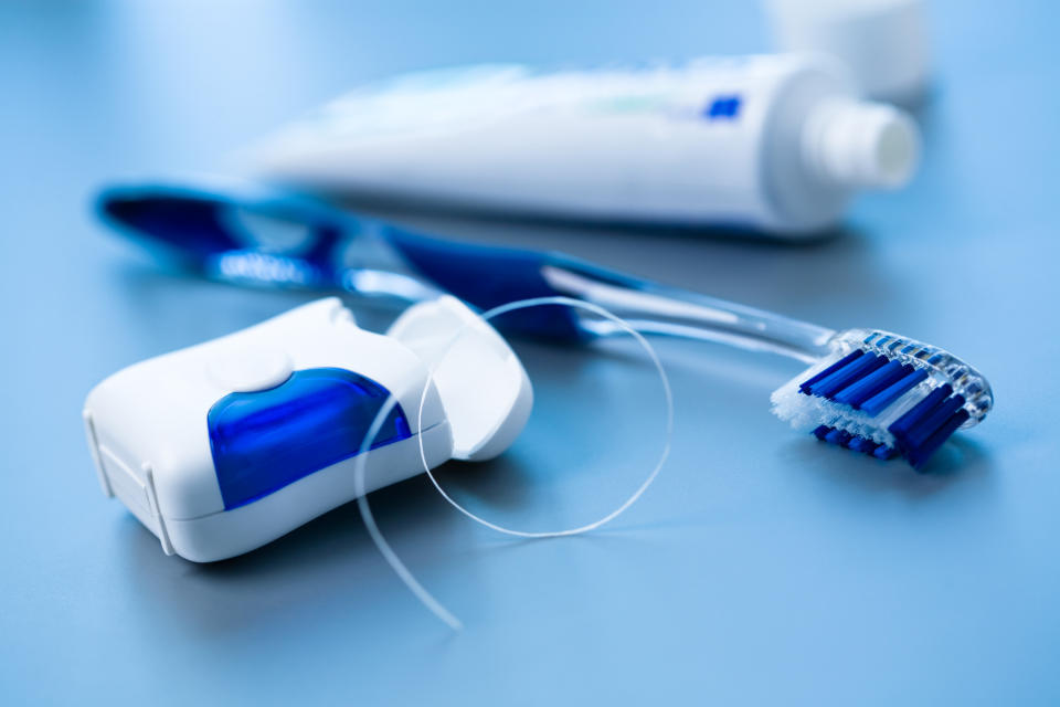 A close-up image showing dental floss, a toothbrush, and a toothpaste tube on a smooth surface, emphasizing dental hygiene items