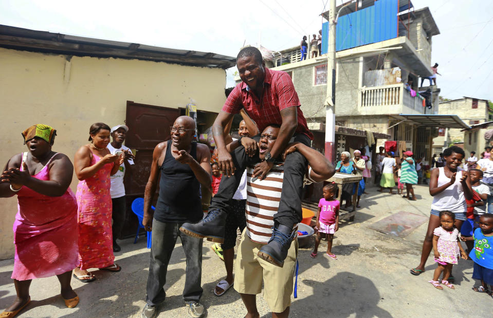 In this May 24, 2019, photo, Barbecue, whose real name is Jimmy Cherizier, is carried by a resident in his neighborhood in Lower Delmas, a district of Port-au-Prince, Haiti. He’s a former policeman, a suspect in the massacre of dozens of men, women and children and a hero in his neighborhood, followed by crowds of adoring residents who consider him their protector. (AP Photo/Dieu Nalio Chery)