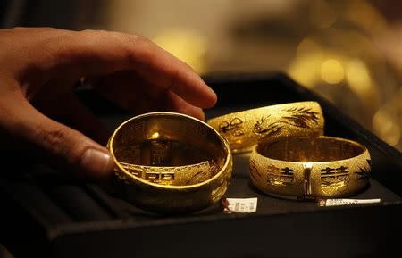 A shop attendant shows two pairs of 24K gold bracelets for Chinese weddings to a customer inside a jewellery store at Hong Kong's Tsim Sha Tsui shopping district April 24, 2013. REUTERS/Bobby Yip/Files