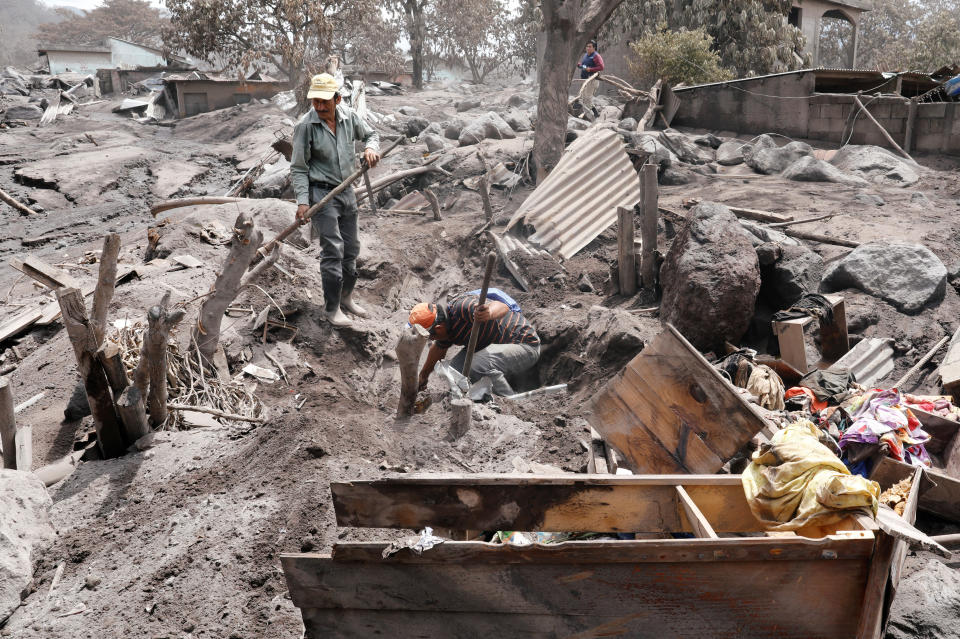 <p>Renato Cortez (L) is helped by friend Alex Ruiz to look for his family at an area affected by the eruption of the Fuego volcano at San Miguel Los Lotes, Escuintla, Guatemala, June 7, 2018. (Photo: Carlos Jasso/Reuters) </p>