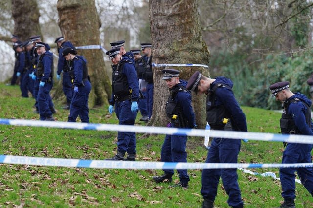 A line of police officers seen behind police cordon tape