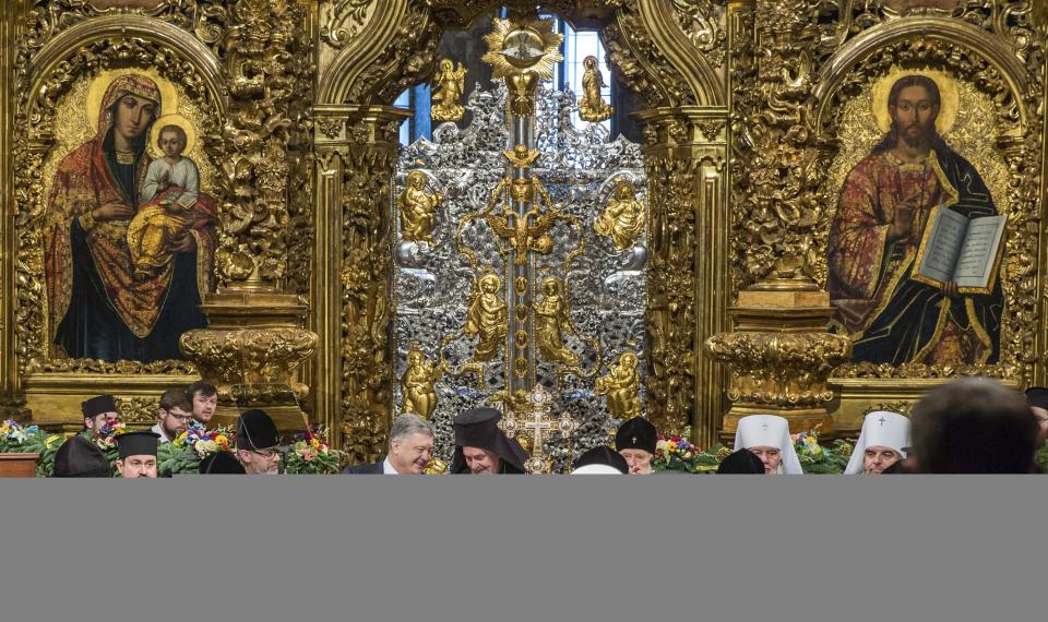 Ukrainian President Petro Poroshenko, center left, and Metropolitan Emmanuel, center right, talk to each other as they attend a closed-door synod of three Ukrainian Orthodox churches to approve the charter for a unified church and to elect leadership in the St. Sophia Cathedral in Kiev, Ukraine, Saturday, Dec. 15, 2018. Poroshenko has told the crowd "the creation of our Church is another declaration of Ukraine's independence and you are the main participants of this historic event." (Mykhailo Markiv, Ukrainian Presidential Press Service/Pool Photo via AP)