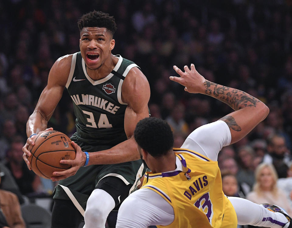 FILE - In this March 6, 2020, file photo, Milwaukee Bucks forward Giannis Antetokounmpo (34) knocks down Los Angeles Lakers forward Anthony Davis as he drives to the basket during the first half of an NBA basketball game in Los Angeles. Antetokounmpo is spending much of his time during the coronavirus-imposed hiatus working out, helping care for his newborn son and playing occasional video games. What the reigning MVP isn’t doing very often is shooting baskets now that the NBA has closed down team practice facilities. (AP Photo/Mark J. Terrill, File)