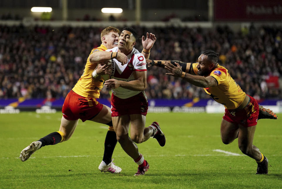 Tonga's Tolutau Koula is tackled by Papua New Guinea's Daniel Russell, left and Justin Olam, during the Rugby League World Cup group D match between Tonga and Papua New Guinea at Totally Wicked Stadium, in St Helens, Merseyside, England, Tuesday, Oct. 18, 2022. (Martin Rickett/PA via AP)