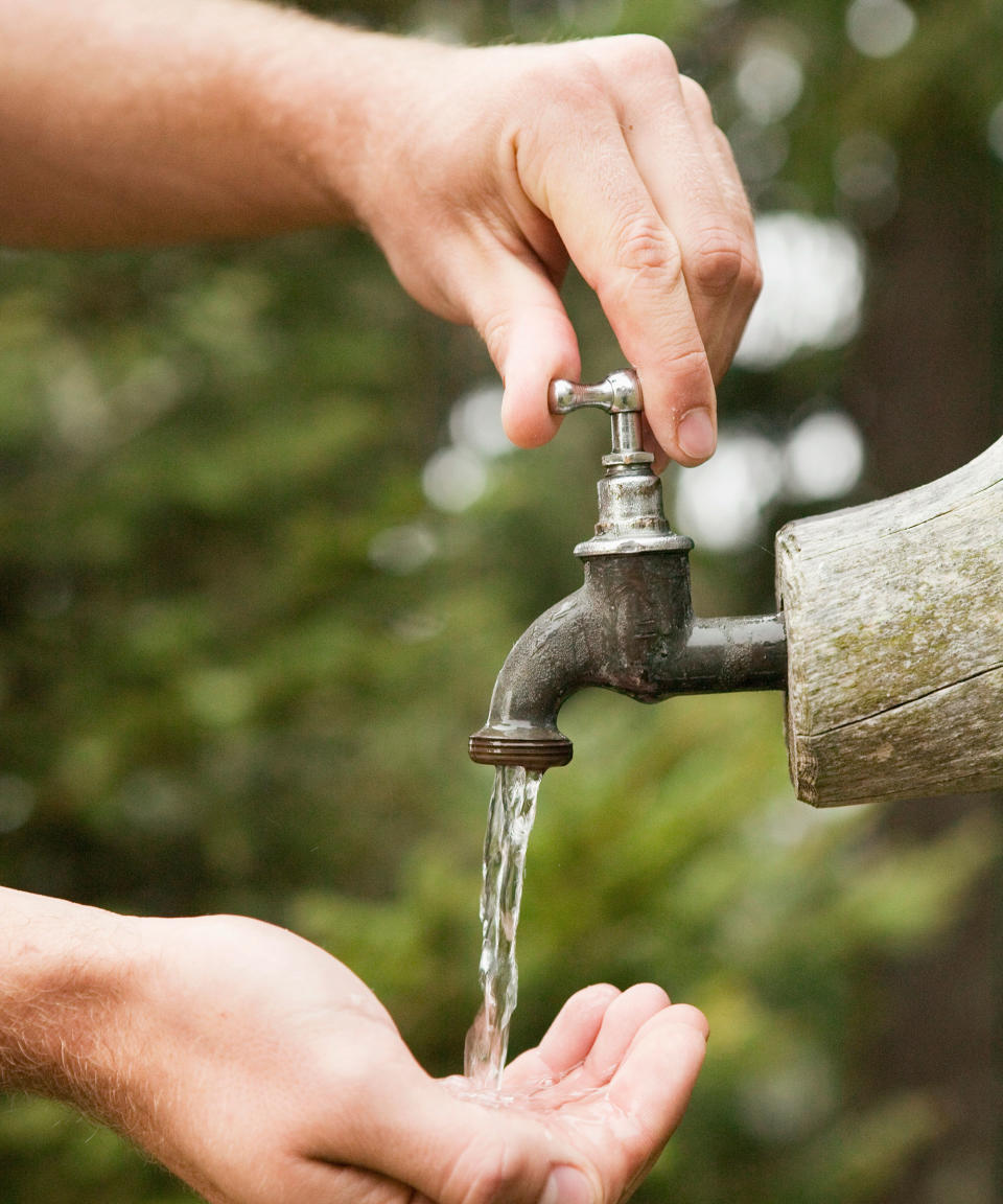 person turning on an outdoor faucet