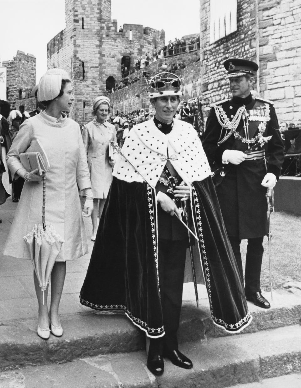 Prince Charles with Queen Elizabeth and Prince Philip, Duke of Edinburgh (right) during the ceremony of Charles' Investment as Prince of Wales at Caernarfon Castle, Gwynedd, Wales, 1st July 1969. They are in the Lower Ward of the castle, for the the third presentation, in which the Queen presents the Prince to the Welsh people.  (Photo by Dennis Oulds/Central Press/Hulton Archive/Getty Images)