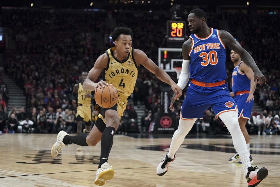 Toronto Raptors forward Scottie Barnes (4) drives past New York Knicks forward Julius Randle (30) during first-half NBA basketball game action in Toronto, Friday, Dec. 1, 2023. (Arlyn McAdorey/The Canadian Press via AP)