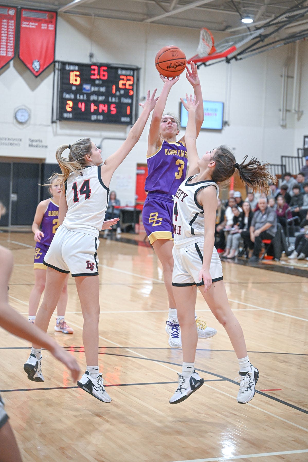 Liberty Union's Ella Brown (14) and Payton Hochradel (4) attempt to block the jump shot of Bloom Carroll's Emily Bratton Monday evening in the Del Barr Gymnasium. The visiting Bulldogs defeated the Lions 65-47. -Jamie Potts/Lancaster Eagle Gazette