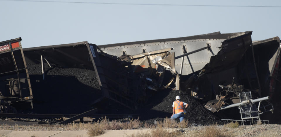 A work observes cars that derailed in an accident over Interstate 25 northbound, Monday, Oct. 16, 2023, north of Pueblo, Colo. (AP Photo/David Zalubowski)