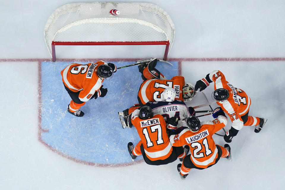 Columbus Blue Jackets' Mathieu Olivier (24) battles for a rebound against Philadelphia Flyers' Tony DeAngelo (77), Scott Laughton (21), Zack MacEwen (17), Carter Hart (79) and Travis Sanheim (6) during the third period of an NHL hockey game, Tuesday, Dec. 20, 2022, in Philadelphia. (AP Photo/Matt Slocum)