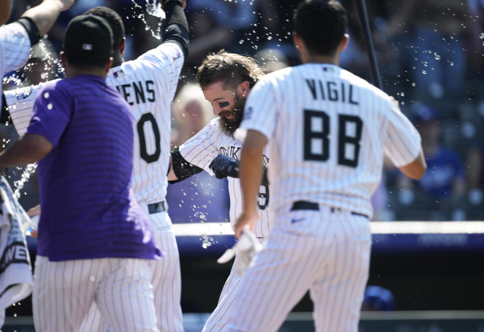 Colorado Rockies' Charlie Blackmon, center, is showered by teammates as Blackmon crosses home plate after hitting a solo home run off Los Angeles Dodgers relief pitcher Phil Bickford during the 10th inning of a baseball game Sunday, July 18, 2021, in Denver. The Rockies won 6-5. (AP Photo/David Zalubowski)