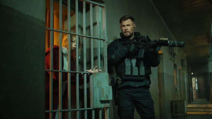 Chris Hemsworth holds a gun outside of a prison cell in Extraction 2.