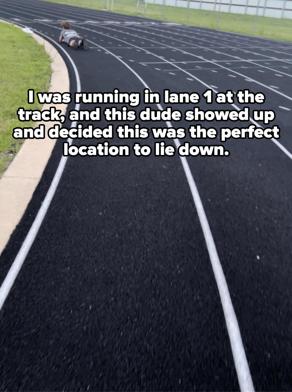 A small child is crawling on the edge of a running track