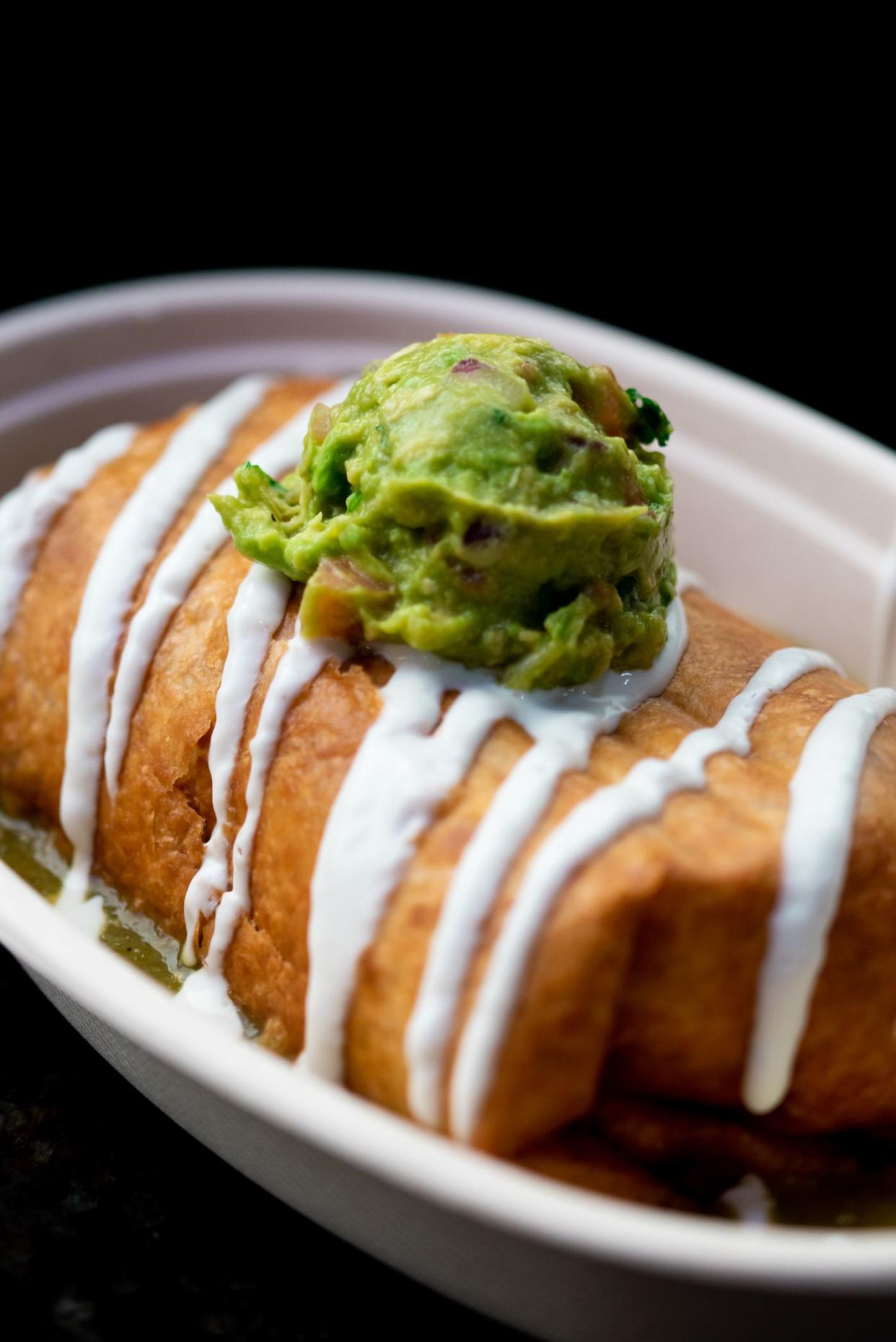 A delicious chimichanga with sour cream and guacamole on top