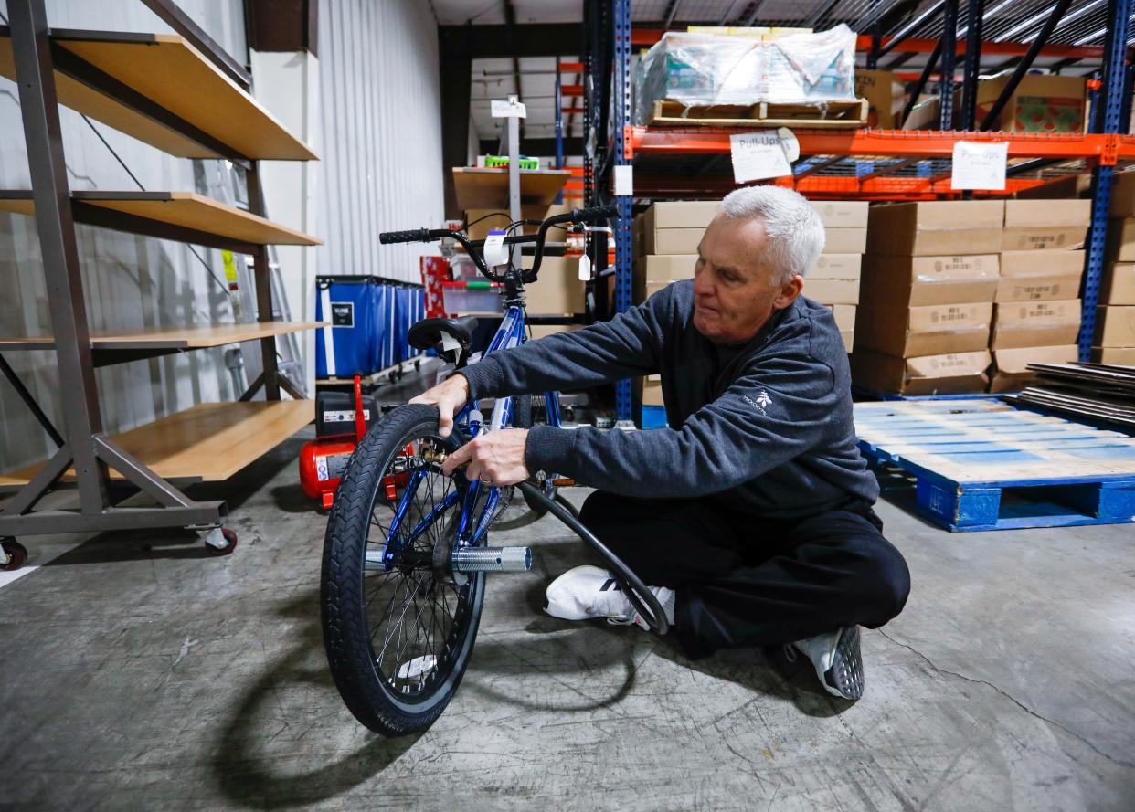 Volunteer Mark Nelson airs up bike tires at the Crosslines warehouse during Share Your Christmas distribution on Friday, Dec. 16, 2022.