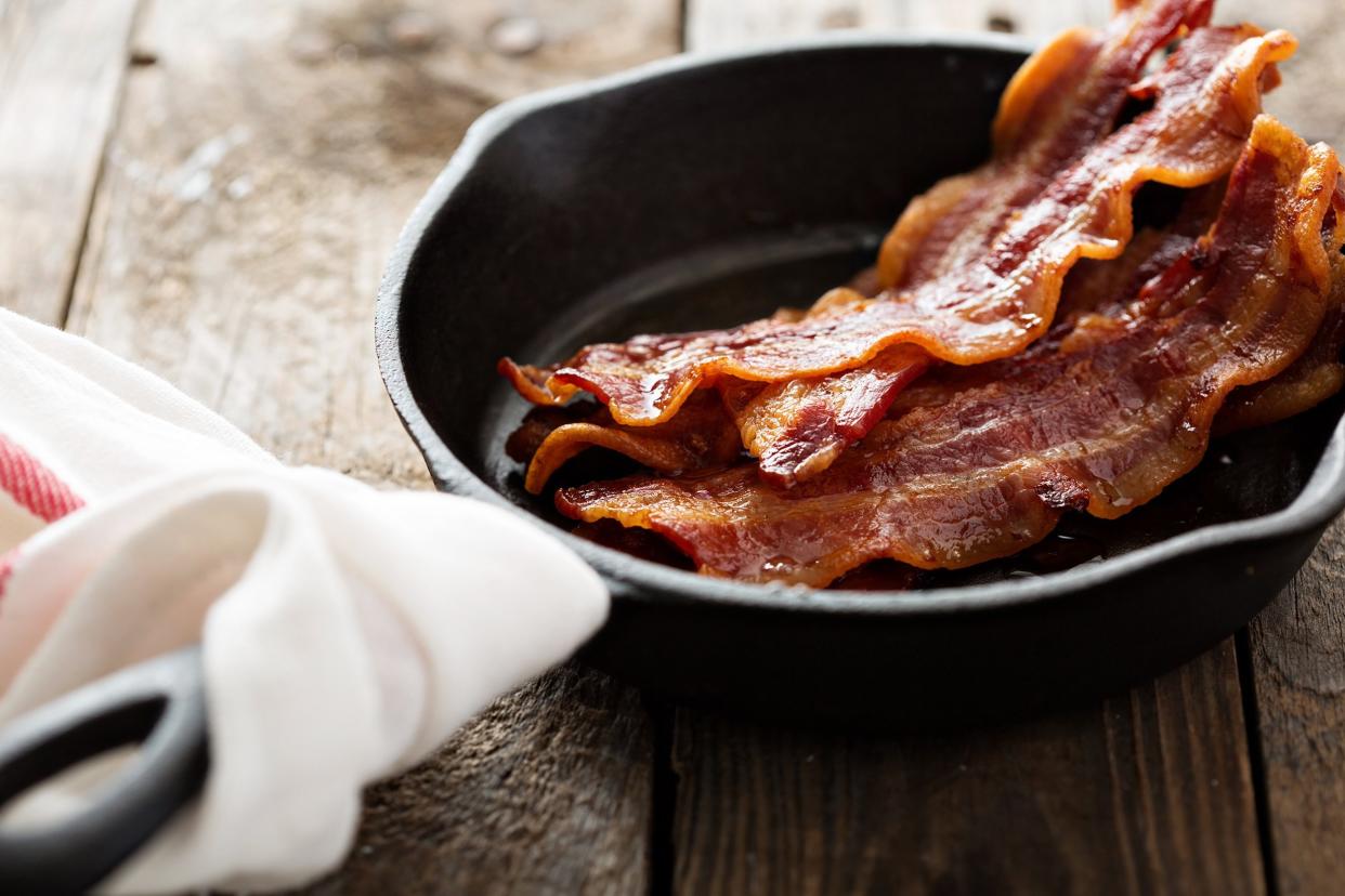 sizzling hot bacon pieces in a cast iron skillet