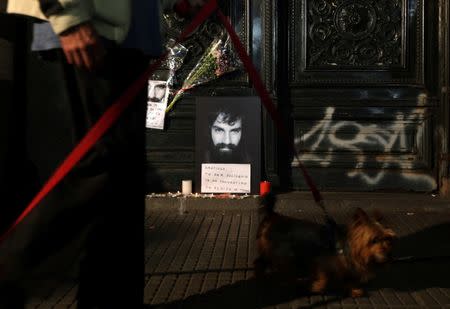 A man walks his dog past a portrait of Santiago Maldonado, a protester who went missing since security forces clashed with indigenous activists in Patagonia on August 1, 2017, placed at the entrance of a judicial morgue in Buenos Aires, Argentina October 20, 2017. REUTERS/Marcos Brindicci