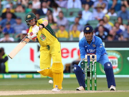 Australia's Steven Smith (L) bats as India's Mahendra Singh Dhoni watches during their One Day cricket match at the Melbourne Cricket Ground, January 17, 2016. REUTERS/Hamish Blair