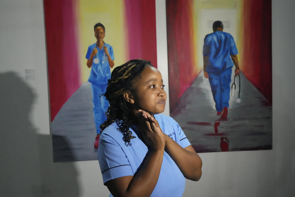 Zimbabwean artist and nurse Deodoris Mawanda stands next to her paintings, in Harare, Wednesday, March 8, 2023. Mawanda is one of 21 female artists whose works have been on show at the southern African country's national gallery since International Women's Day on March 8. The exhibition is titled "We Should All Be Human" and is a homage to women's ambitions and their victories, art curator Fadzai Muchemwa said. (AP Photo/Tsvangirayi Mukwazhi)