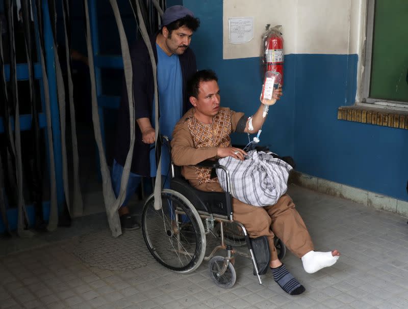 A hospital worker assists an injured person to an ambulance at a hospital after an attack in Kabul