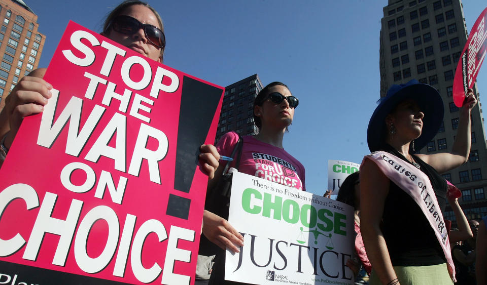 Protesters hold signs reading "stop the war on choice" and "choose justice"