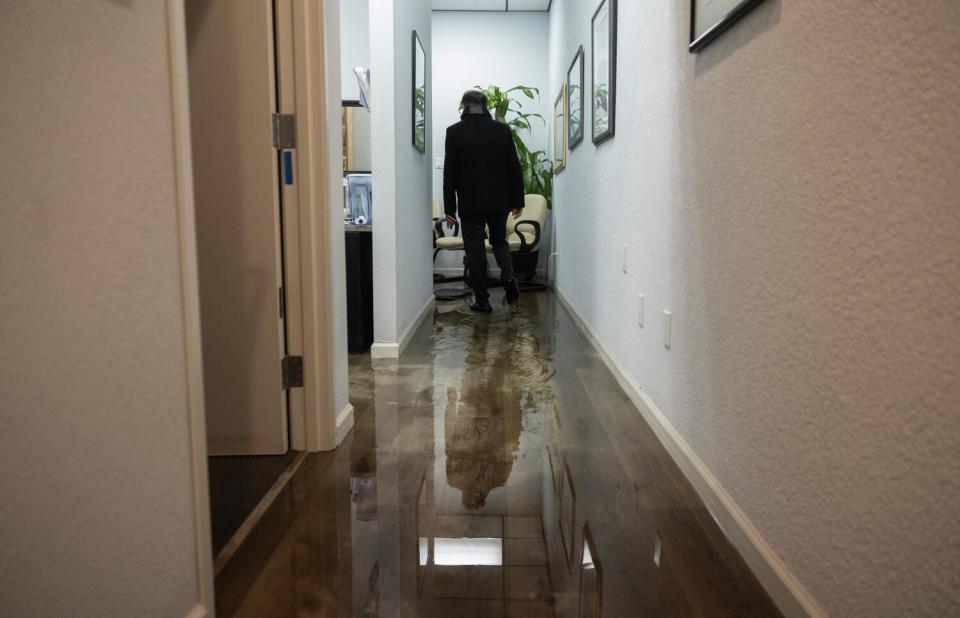 Silhouette of a man sweeping water out of his shop.