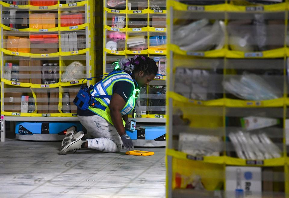 Shineka Robinson checks one of the pod-moving robots to ensure it moves correctly inside the new Amazon Fulfillment Center on Thursday, October 13, 2022, in Sioux Falls.