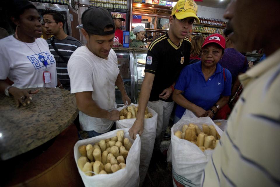 In this March 17, 2017 photo, employees of the Minka state-run bakery carry bags of cheap bread to be distributed to state-run grocery stores in Caracas, Venezuela. The government said it was taking over the Mansion’s Bakery for 90 days, turning control over to a pro-government neighborhood committee given the task of distributing bags of staples door-to-door. (AP Photo/Fernando Llano)