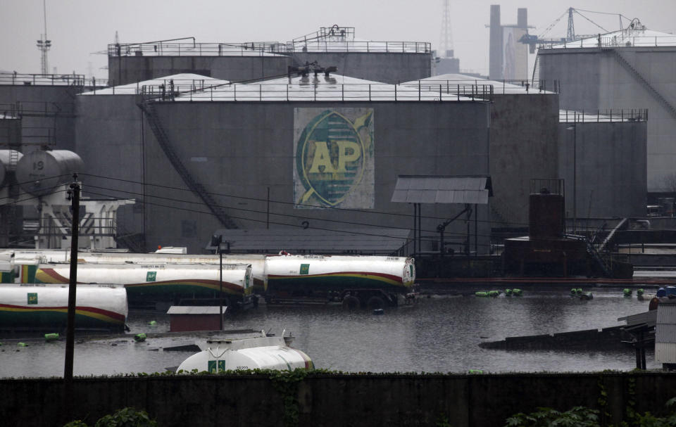 FILE- A tank farm and oil trucks are half submerged after a downpour at an oil terminal in Lagos Nigeria, on July. 11, 2011. Nigerian state gas company has declared a force majeure after floods hindered gas operations, raising concerns among analysts about the West African nation's capacity to meet local and international demands. (AP Photo/Sunday Alamba, File)