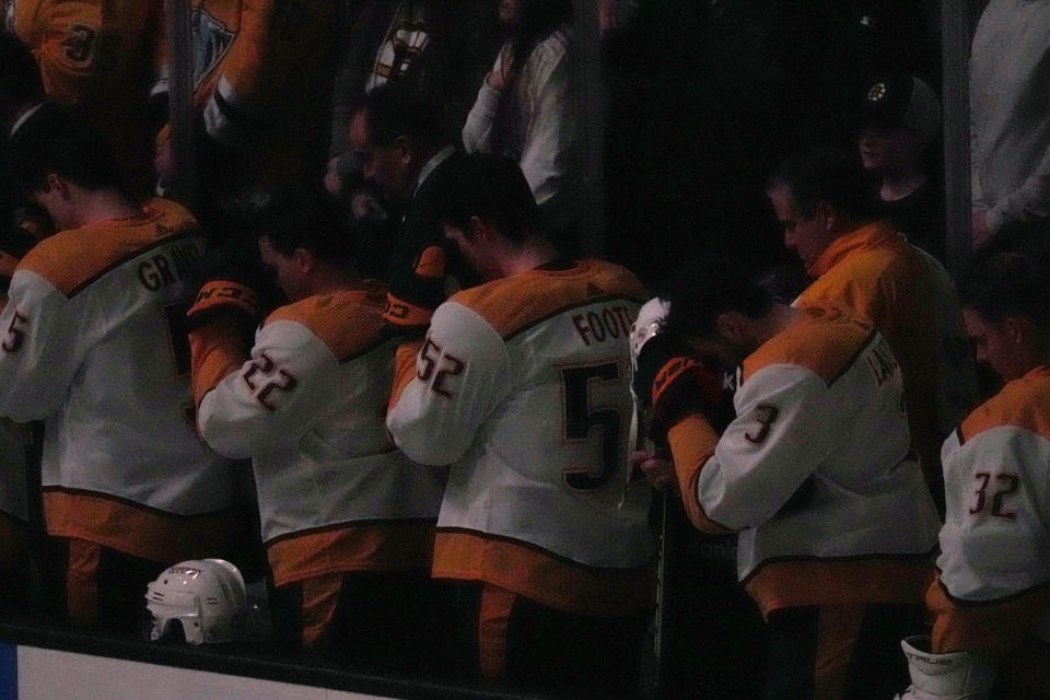 House lights are dimmed as Nashville Predators pause during a moment of silence for the victims of the Covenant School shooting, before the team's NHL hockey game against the Boston Bruins, Tuesday, March 28, 2023, in Boston. (AP Photo/Charles Krupa)