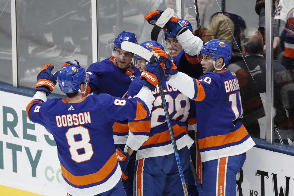 New York Islanders left wing Anders Lee (27), second from right with his back against the glass, celebrates with teammates, including defenseman Noah Dobson (8), left wing Michael Dal Colle (28), and center Derick Brassard (10) after scoring a goal during the third period of an NHL hockey game, Monday, Jan. 6, 2020, in Uniondale, N.Y. The Islanders defeated the Avalanche 1-0 on Lee's game-winning goal. (AP Photo/Kathy Willens)